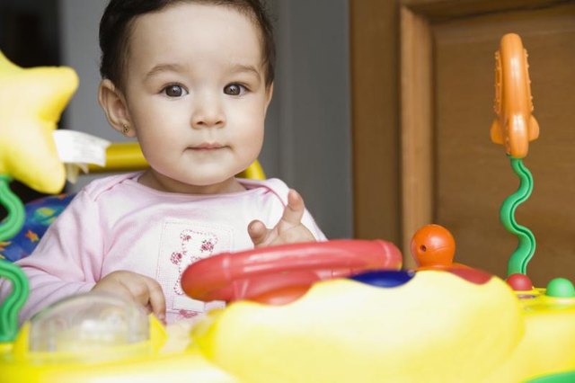 A baby girl sitting in a colorful activity chair. A baby girl sitting in a colorful activity chair.
