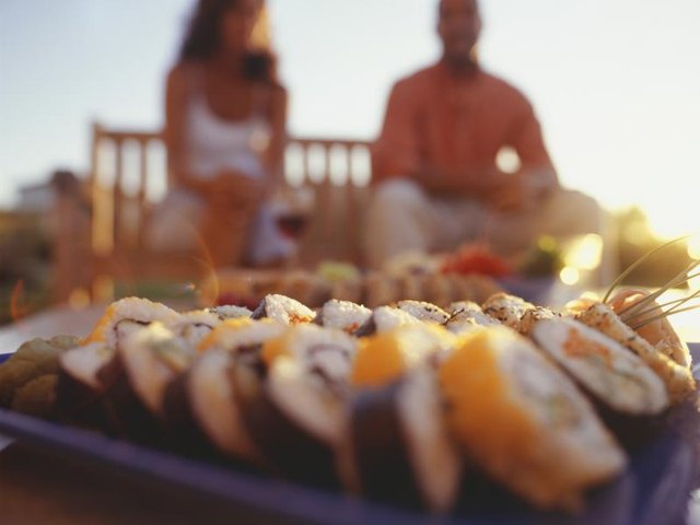 A close-up of a sushi patter on a seaside table.