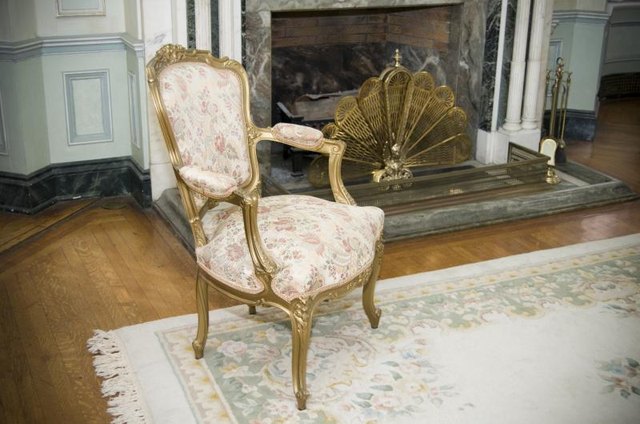 A chair painted gold in front of gold accessories on the hearth.
