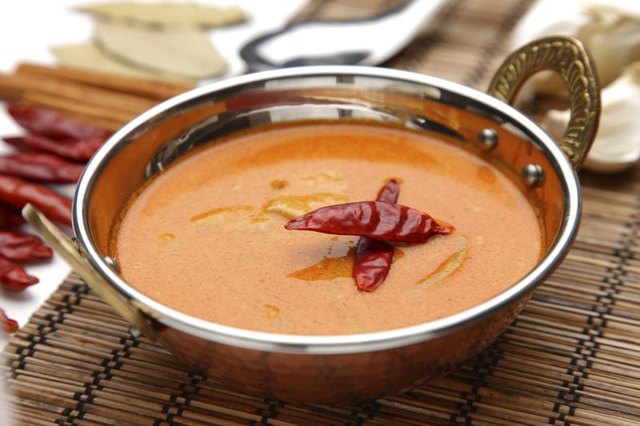 A bowl of Thai red curry with chili peppers.