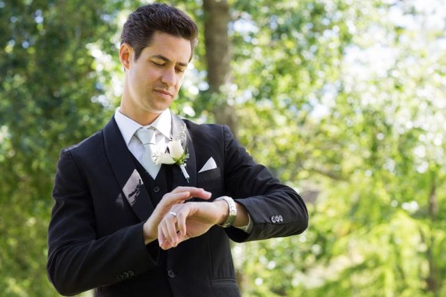 A groom is checking his watch.