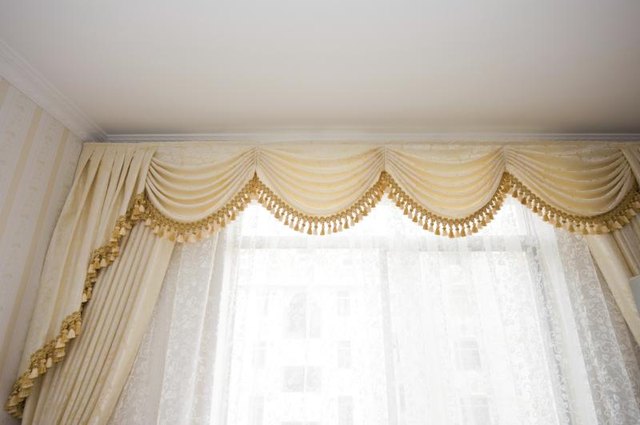 Floor length formal drapes with a tassled fringe over sheer curtains.