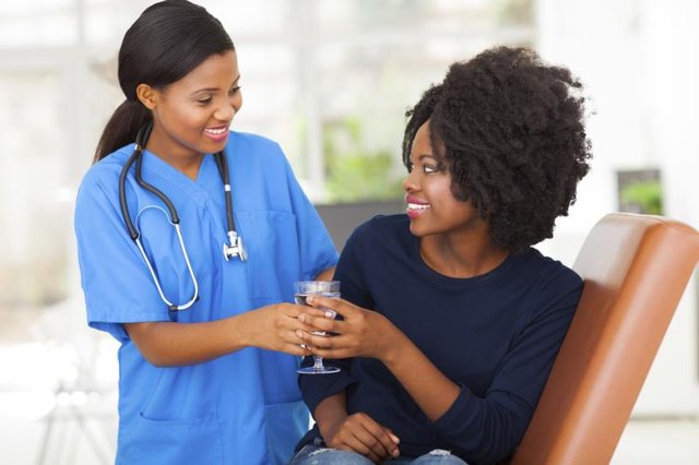 A medical assistant hands a patient a glass of water
