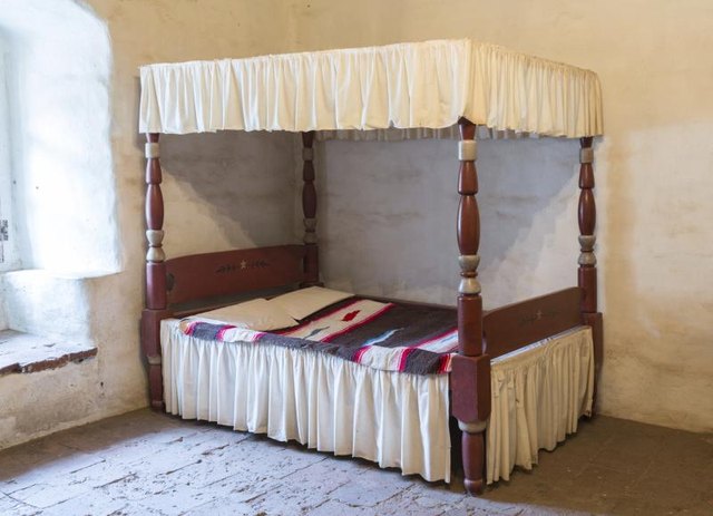 Rustic Mexican bed in stucco room.