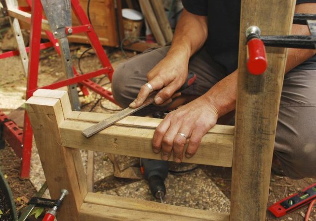 Carpenter filing a wood chair.