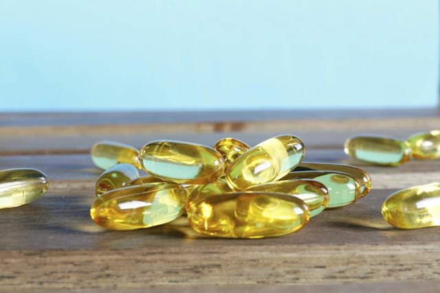 Fish oil supplements on a wooden table. Fish oil supplements on a wooden table.