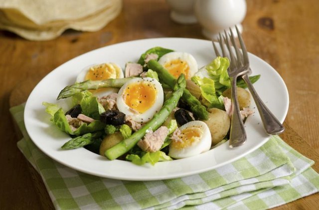 Tuna salad in a bowl with asparagus, potatos, olives and boiled eggs.