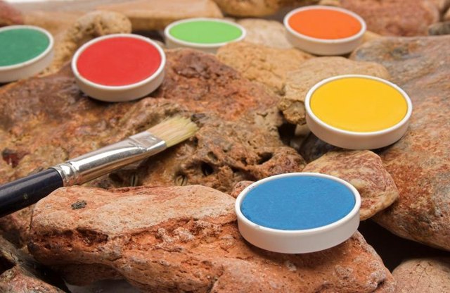 Colorful paint cells and a paintbrush on red rock.