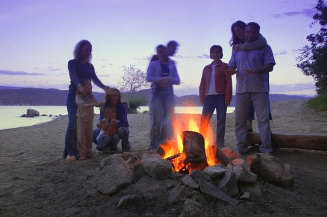 A family at a bonfire near the water.
