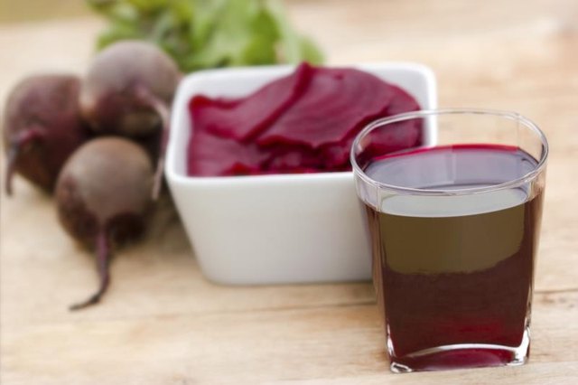 A cup of beet juice next to a bowl of sliced beets