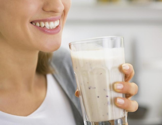 A woman drinks a smoothie.