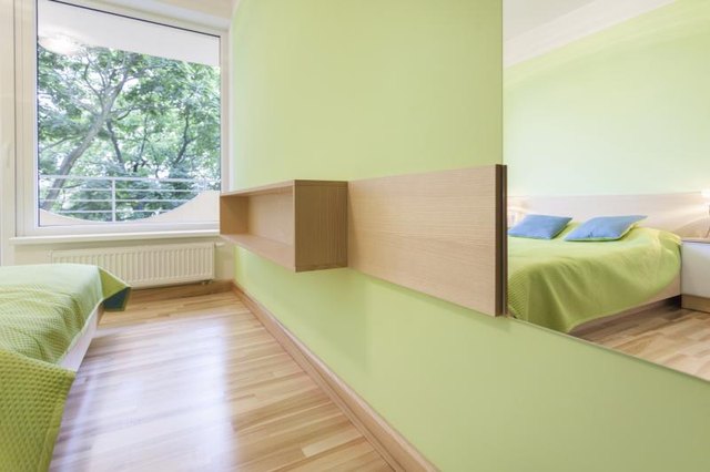 A view from the mirror of a pale green modern bedroom.