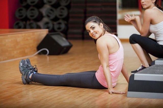Two women in a gym studio using an aerobic step.