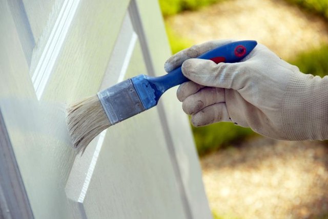 A person painting a wooden door with a brush.