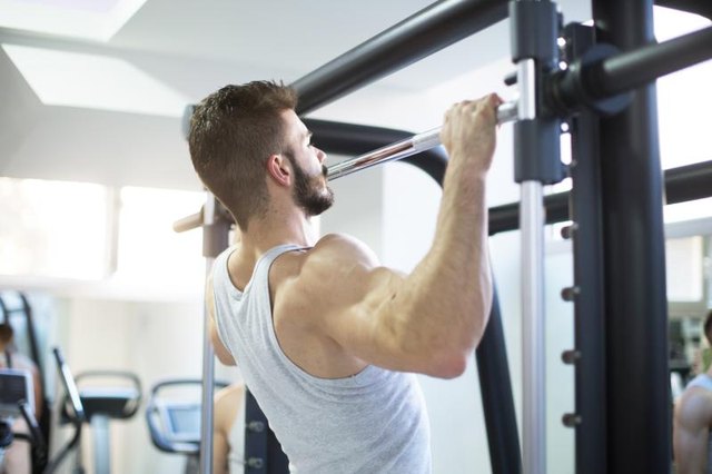 A man does a pull-up at a gym.