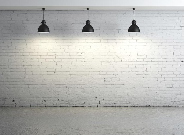 Lights against a brick wall shining on concrete floor