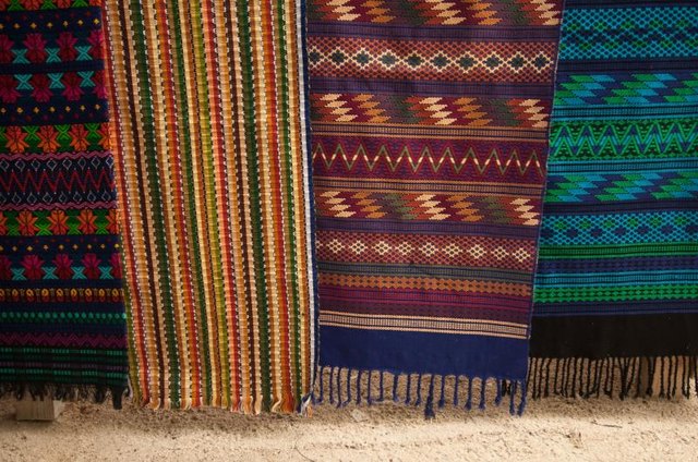 Colorful woven rugs hanging at a market.