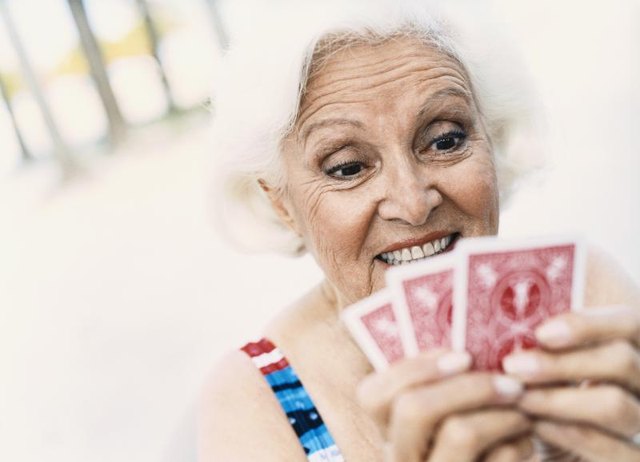A mature woman holding playing cards.