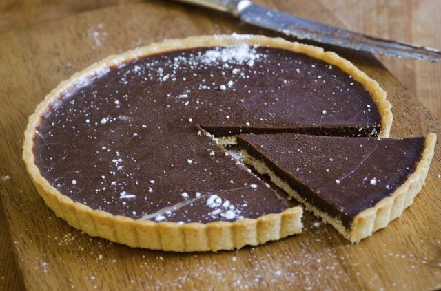 A freshly cut chocolate tart on a wooden table.