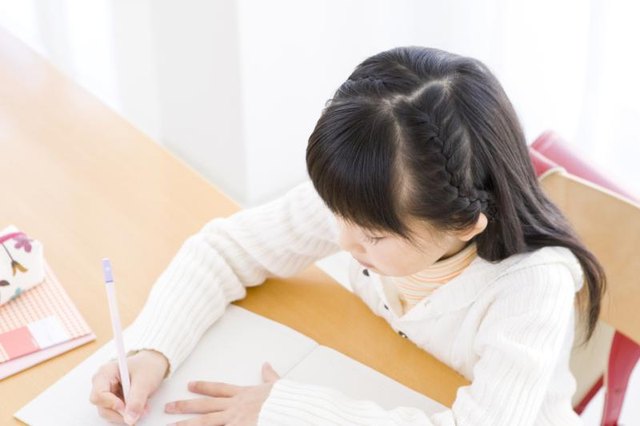 Young student writing at desk.