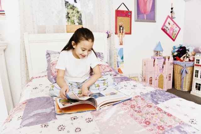 A young girl is sitting in her colorfully decorated bedroom.