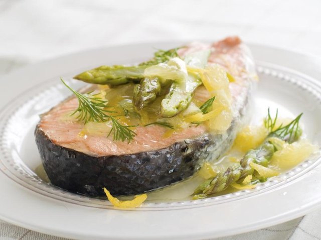 A poached salmon filet topped with asparagus and orange zest.