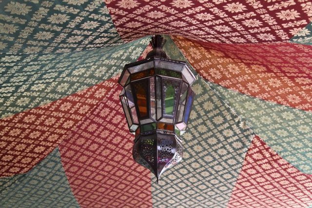 A Moroccan lamp hanging from the center of an awning.