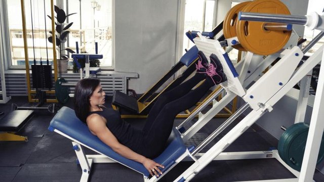 A woman perfoming leg repetitions on a machine.