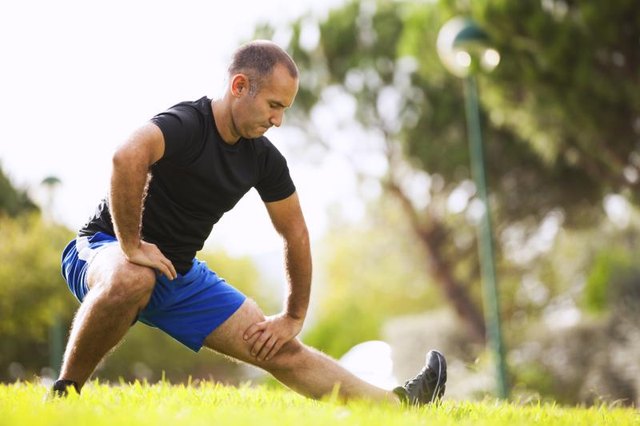 A man streches in a city park. A man streches in a city park.