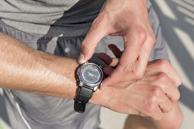 A close-up of a man looking at his watch while working out.