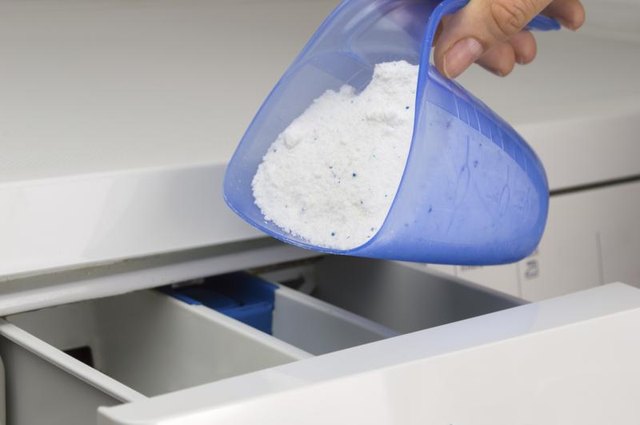 Close-up of woman pouring detergent into washing machine.