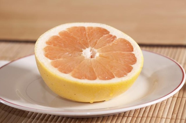 A sliced grapefruit half on a plate.