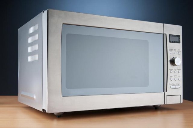 A hand opening a microwave oven.