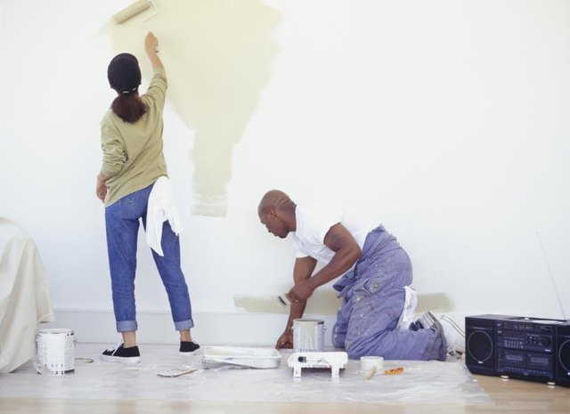 A couple painting a wall with rollers. A couple painting a wall with rollers.