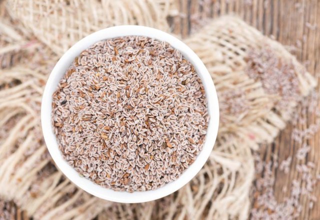 An overhead view of psyllium husk seeds in a bowl on a rustic table. An overhead view of psyllium husk seeds in a bowl on a rustic table.