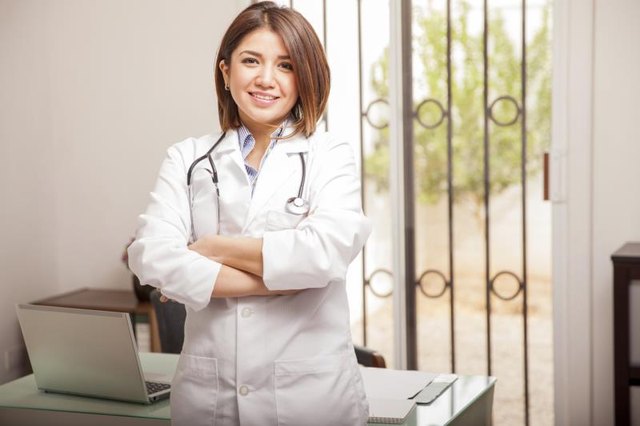 A nutritionist standing in her office in front of a desk with a computer.