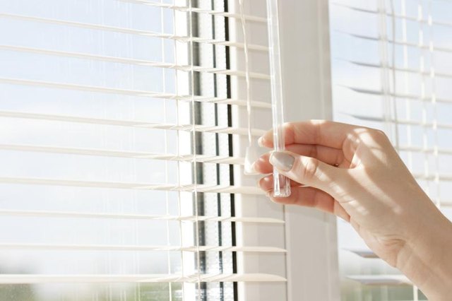 Close-up of woman's hands closing blinds.