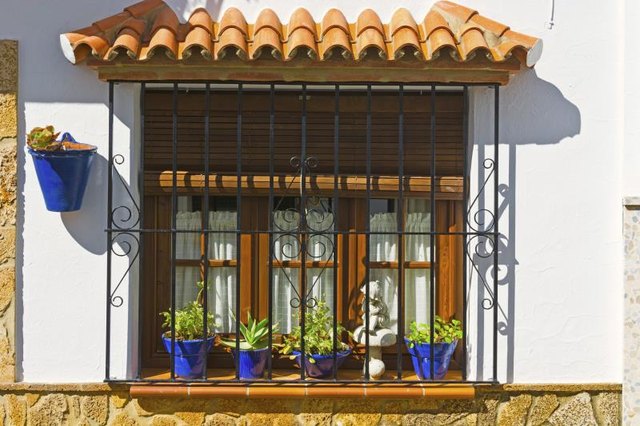 The front of a Spanish style home with blue flower pots