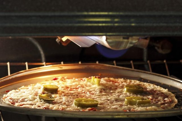 A pizza is being baked using the oven broiler