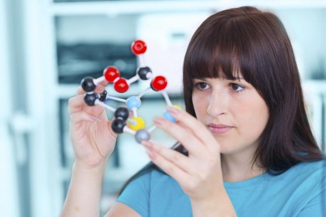 A teenage girl building a molecule model in a classroom. A teenage girl building a molecule model in a classroom.