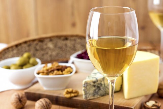 Wine glass with cheese and nuts in background