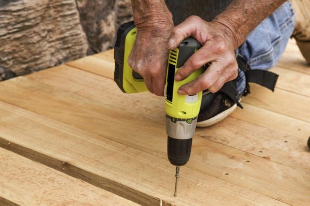 A construction worker is using a cordless drill.