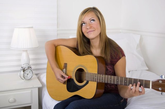 Girl playing guitar in dorm room.