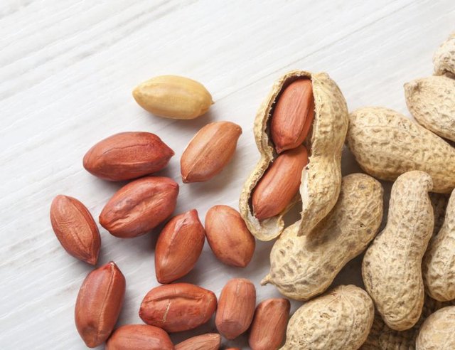Peanuts and shells on a wood table.