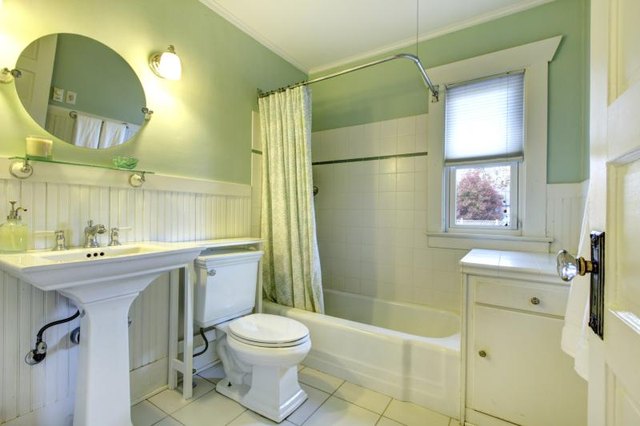 White tile, wainscoting and fixtures in a pale green bathroom.