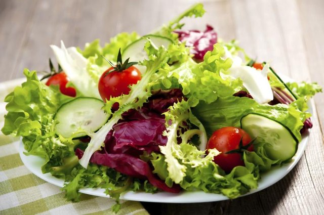 A plate of salad on a wooden table.