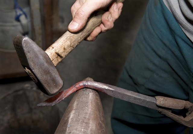 Using hammer to bend hot metal object