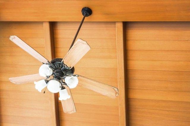 A close-up of a ceiling fan hanging from a wooden peak.