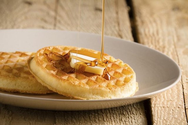 Plate of waffles with syrup being drizzled on top.