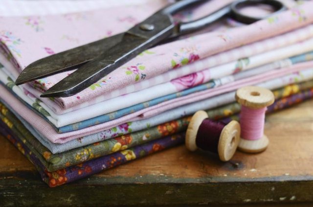 Antique scissors resting on a pile of folded fabrics.